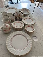 Full display of the Golden Rose dinnerware set showing plates, cups, serving pieces arranged on a table