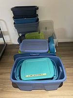 Wide shot of stacked plastic storage bins of various sizes and colors including a blue bin labeled 'X-mas decorations'