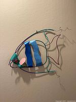 Front-facing view of the large vintage metal fish sculpture wall art, showing the colorful wire and metal strip construction and colors.