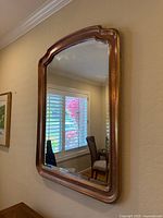 Full view of the large wooden framed mirror showing its overall shape and placement on wall