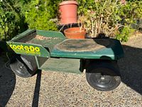 Mobile gardening seat with four wheels, green color, tool tray on side, used for gardening while seated