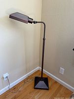 Full view of the vintage adjustable floor lamp standing against a wall, showing the entire lamp including the cord and square base.