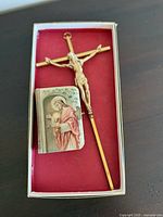 Brass crucifix and miniature prayer Bible together in a box with red lining