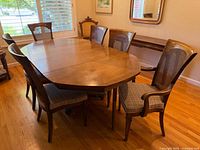 Rectangular dining table in dining room with six chairs around it, wood finish, hardwood floor.