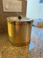 Side view of vintage cylindrical metal ice bucket showing gold bands and brushed metal finish.