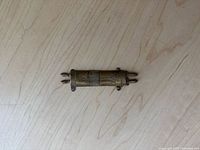 Vintage mezuzah case front view showing gilded brass and copper surface with embossed Star of David design and scroll shape.