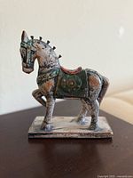 Side view of vintage painted battle war horse sculpture showing decorative armor and rectangular base.