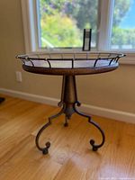 Full view of vintage coffee table showing the metal railing edge and tripod base with scroll details.