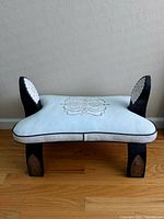 Front view showing the light blue saddle-style cushioned seat with decorative pattern and black trim along edges.