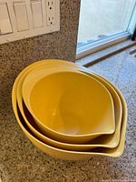 Stacked set of three yellow vintage Williams-Sonoma mixing bowls showing nested design and pouring spouts.