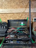 Closed view of three-drawer steel toolbox standing upright next to measuring stick