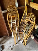 Three pairs of traditional wooden snowshoes leaning against wall