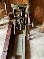 Full view of beam boring machine with auger bit attached and wood base