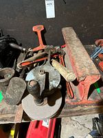 Group of tools on bench including grinder, anvil section, clamps, hammer