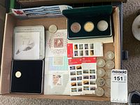 Overview of lot showing stamp booklets, souvenir sheets, green coin case with three coins, presentation tin with coin, and loose coins/tokens