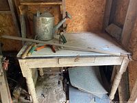 Overall view of potting table with watering can, bar, sprinkler and tools