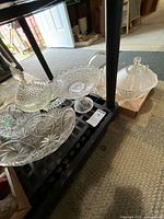 Group of pressed glass pieces on shelf showing basket, bowls, covered dishes