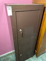 Front view of brown metal safe cabinet with key in lock
