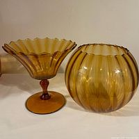 Front and side view showing both amber Empoli optic glass vase and bowl set on white background
