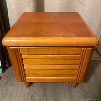 Front view of petite Art Deco nightstand showing rounded front corners, layered door panel, and rounded feet.