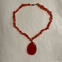 Full view of 18 inch carnelian chip bead necklace with teardrop pendant arranged in circle.