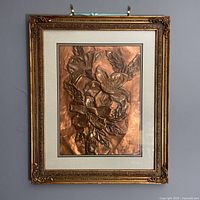 Full view of embossed copper floral artwork framed in antique gold frame with double mat.