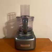 Front angle of the Cuisinart food processor showing the grey base, clear work bowl, and feed tube
