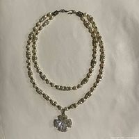 Full view of the double strand faux pearl and crystal necklace laid flat, showing the hook clasp and four leaf clover pendant.