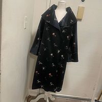 Full-length view of navy blue silk coat with embroidered floral designs, showing button front and wide collar on mannequin.