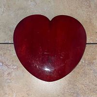 Top view of the heart-shaped wooden box closed, showing the red finish with some surface scratches.