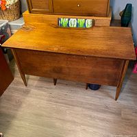 Full view of the desk showing the surface with damage at one corner and the overall Mid-Century Modern wooden construction