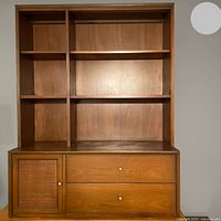 Front view of MCM storage unit showing six cubbies, two drawers, and one cabinet door with woven rattan panel and metal knobs.