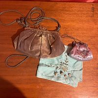 Photo of two evening purses and a silk embroidered handkerchief on a wooden surface