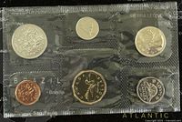 Photo of six coins inside original plastic packaging showing different designs and colors including copper, silver, and gold tones.