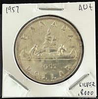 Reverse side of the 1957 Canadian silver 1 dollar coin featuring two voyageurs in a canoe and inscription.