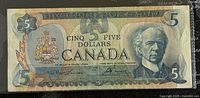 Front of 1979 Canadian five dollar banknote featuring Sir John A. Macdonald portrait, Canadian coat of arms, numbered 5 and bilingual text.