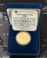 1992 Royal Canadian Mint commemorative dollar coin in protective case inside blue velvet presentation box with insert card describing design and specifications.