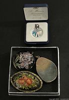 Four jewelry pieces: three pendants and one brooch laid out together showing various painted and stone details.