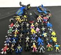 Lot of 50 Fisher-Price Imaginext figures and two vehicles displayed, featuring characters from DC Super Friends and Power Rangers.
