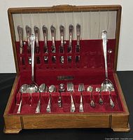 Full view of the 60-piece Rogers silverplate flatware set displayed in the wooden box with red velvet lining. Contains assorted knives, forks, and spoons, some serving utensils.