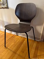 Single IKEA SIGTRYGG dining chair from the front, showing curved backrest and seat in dark wood finish with black metal legs