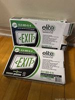 Two boxed Elite Lighting LED Exit Signs showing product labels and model number ELX-603-G-B
