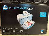 Box front showing HP Photosmart A532 printer image and key features including 5x7 inch photo printing, 2.4-inch color display, fold-up paper tray, memory card slots