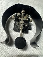 Photo showing the complete Morse code telegraph key with black base, metal components and curved handle.