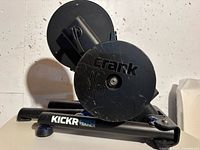 Front view of the black metal Wahoo Fitness bike trainer with visible crank resistance unit and foldable legs on floor.