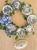 Full view of wreath showing arrangement of blue & white plates and milk glass dish nearby