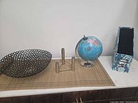 Overall view showing metal bowl, candle holder, globe, magazine holder on woven runner