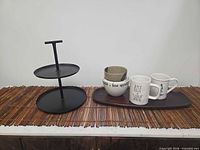 All items arranged on stick mat: metal stand, nesting bowls, small bowl, mugs, wood tray