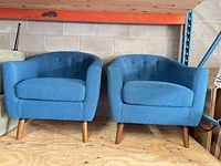 full view of both matching blue-teal armchairs on plywood floor