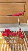 Full view of red toddler scooter standing upright